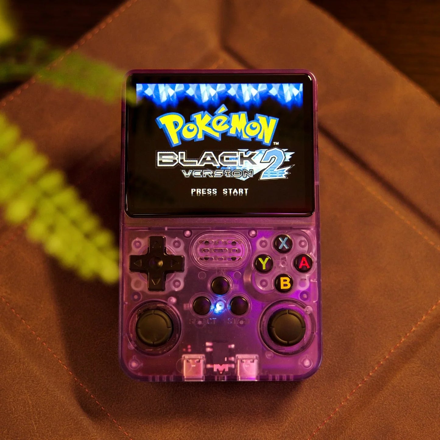 Handheld gaming console displaying 'Pokémon Black Version 2' on a brown surface.